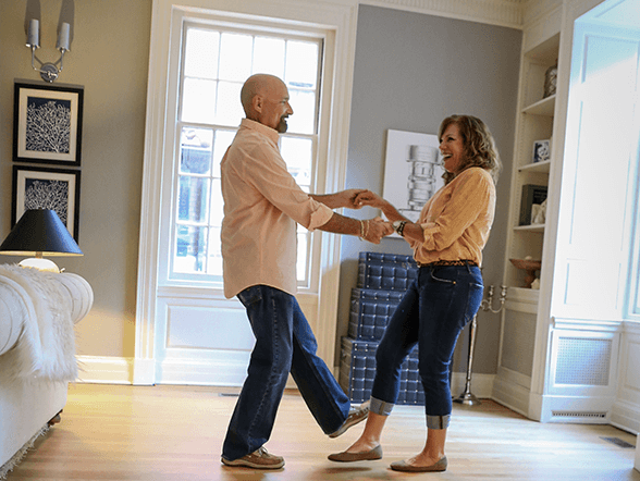 Couple dancing in a bright living room with hardwood flooring